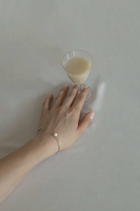 UMIAR biżuteria - Minimalistyczna bransoletka ze sztywnej, cienkiej półobręczy zakończonej naturalną perłą. Dopracowany, opływowy kształt wspaniale podkreśla nadgarstek. Prosta, dyskretna forma sprawia, że bransoletka zyskuje elegancki, klasyczny charakter. Model inspirowany kolczykami GRANO BACCA. W całości wykonana ze szlachetnych materiałów. Dostępna w 2 wariantach: srebrze 925 i srebrze 925 pozłacanym 24-karatowym złotem.
