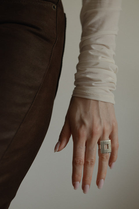 Odkryj wyrazisty pierścionek z kwadratowym elementem i ryflowanym wzorem. Nowoczesna forma, subtelne "okienko" i ponadczasowa elegancja. Idealny do stylizacji power dressing i minimalistycznych zestawów. Sprawdź kolekcję UMIAR!