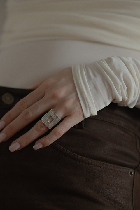 Odkryj wyrazisty pierścionek z kwadratowym elementem i ryflowanym wzorem. Nowoczesna forma, subtelne "okienko" i ponadczasowa elegancja. Idealny do stylizacji power dressing i minimalistycznych zestawów. Sprawdź kolekcję UMIAR!