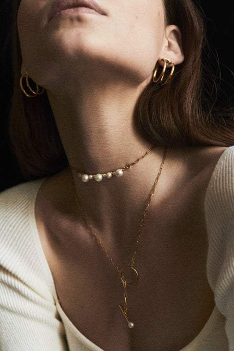 Niezwykle efektowny naszyjnik typu choker z kolekcji UMIAR biżuteria zachwyca różnorodnością pereł, łańcuszkiem i asymetryczną zawieszką w kształcie koła. Ręcznie wykonany ze szlachetnych materiałów, dostępny w wersjach ze srebrem 925 i srebrem 925 pozłacanym 24-karatowym złotem. To połączenie wzornictwa z rzemiosłem tworzy wyjątkową biżuterię, która emanuje elegancją i stylem.