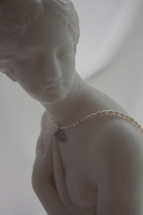 Wyjątkowy naszyjnik choker, stworzony z połączenia srebrnego łańcuszka, delikatnego wisiorka w kształcie połamanej muszli i naturalnych pereł. Regulowana długość łańcuszka pozwala nosić go przy szyi lub nieco niżej. Ręcznie wykonany ze szlachetnych materiałów przez UMIAR biżuteria. Dostępny w dwóch wariantach: srebrze 925 i srebrze 925 pozłacanym 24-karatowym złotem.